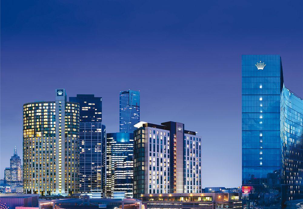 Crown Metropol Melbourne Hotel Exterior foto The photo showcases a city skyline at dusk, featuring a cluster of modern high-rise buildings and skyscrapers. The structures are illuminated against the evening sky, creating a vibrant atmosphere. Prominently displayed on the right is a tall buildin