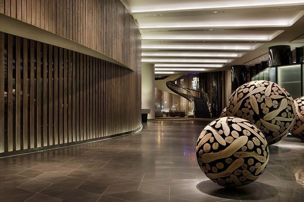 Crown Metropol Melbourne Hotel Exterior foto The photo shows a modern and stylish interior space, likely of a hotel lobby or a public area. The design features a curved wall made of wood, creating a warm ambiance. The flooring appears to be dark stone tiles, contributing to the contemporary loo